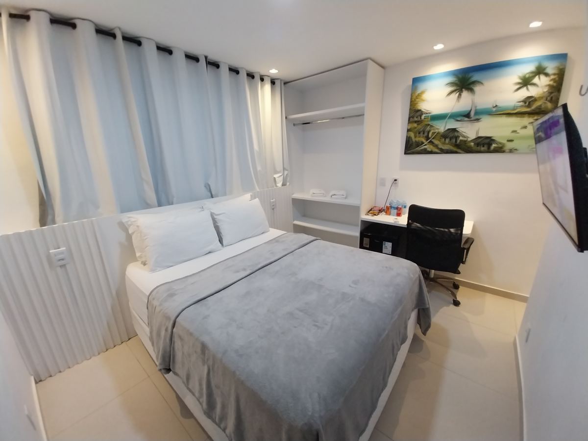 Quarto de casal com cortinas, mesa e ar-condicionado